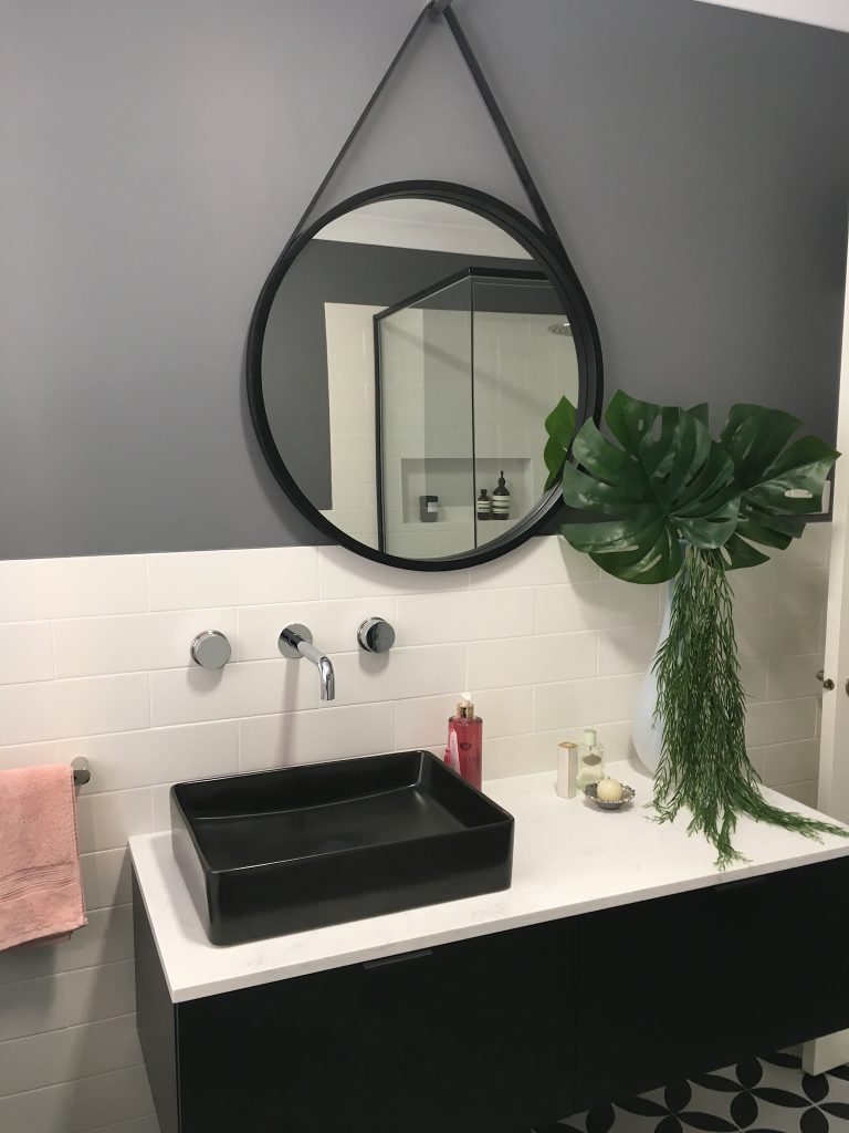 Black round mirror reflecting adding character to the bathroom - bathroom renovation by Master Bathrooms & Kitchens.