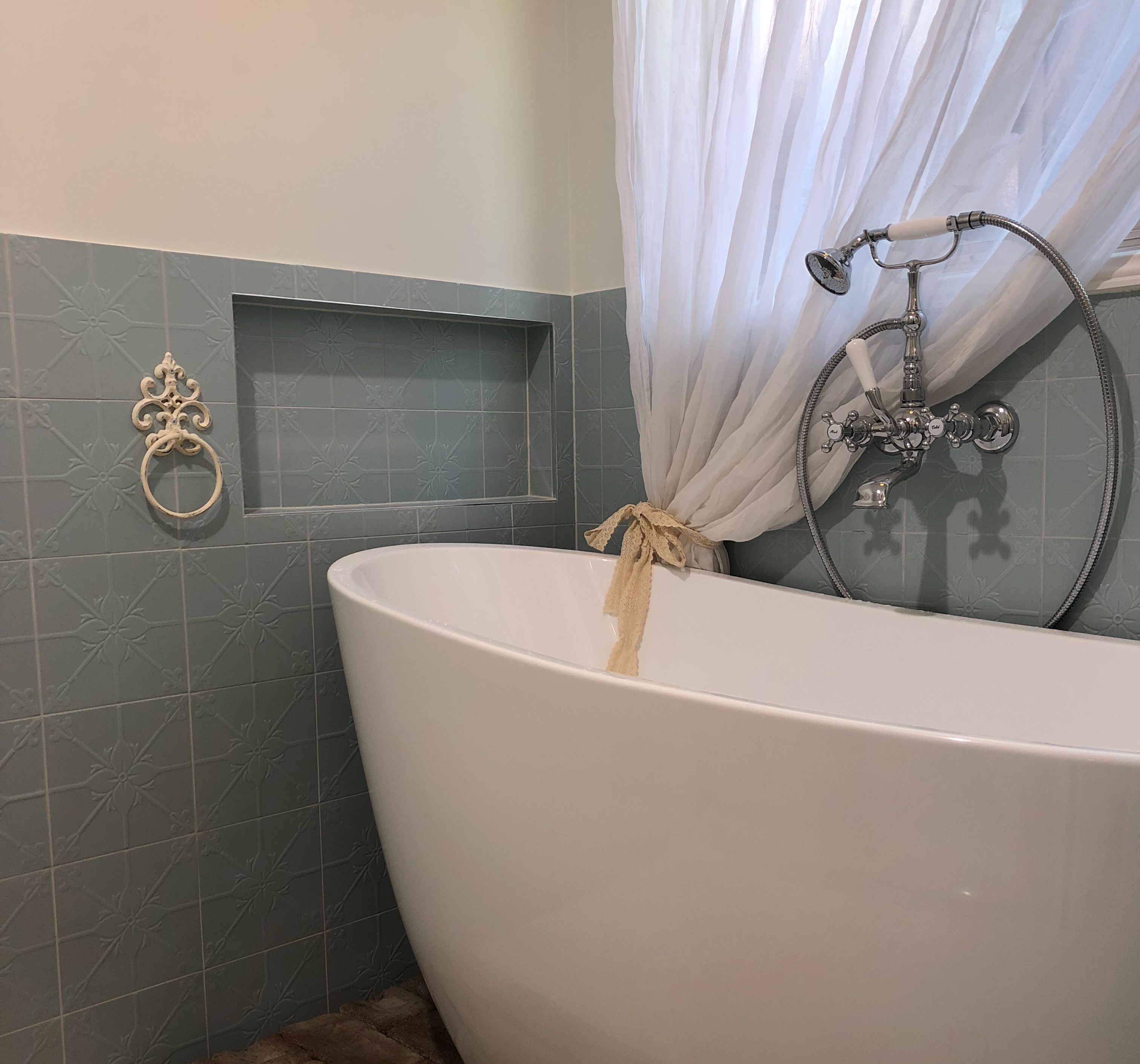 Modern free standing bath with antique tap fittings and built-in niche