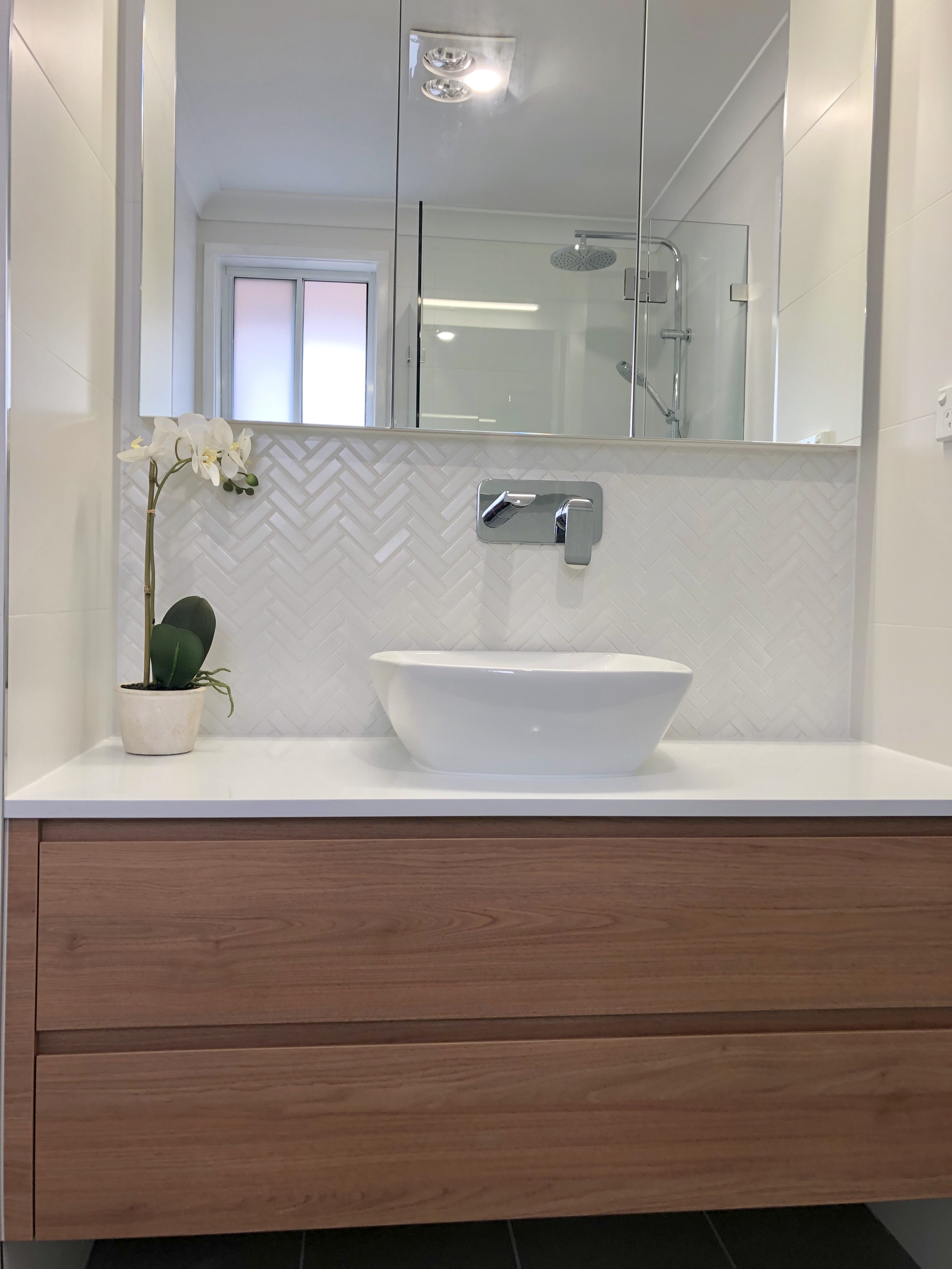 Stunning custom made timber vanity with stone benchtop, herringbone tile and custom shaving cabinet - bathroom renovation by Master Bathrooms & Kitchen.