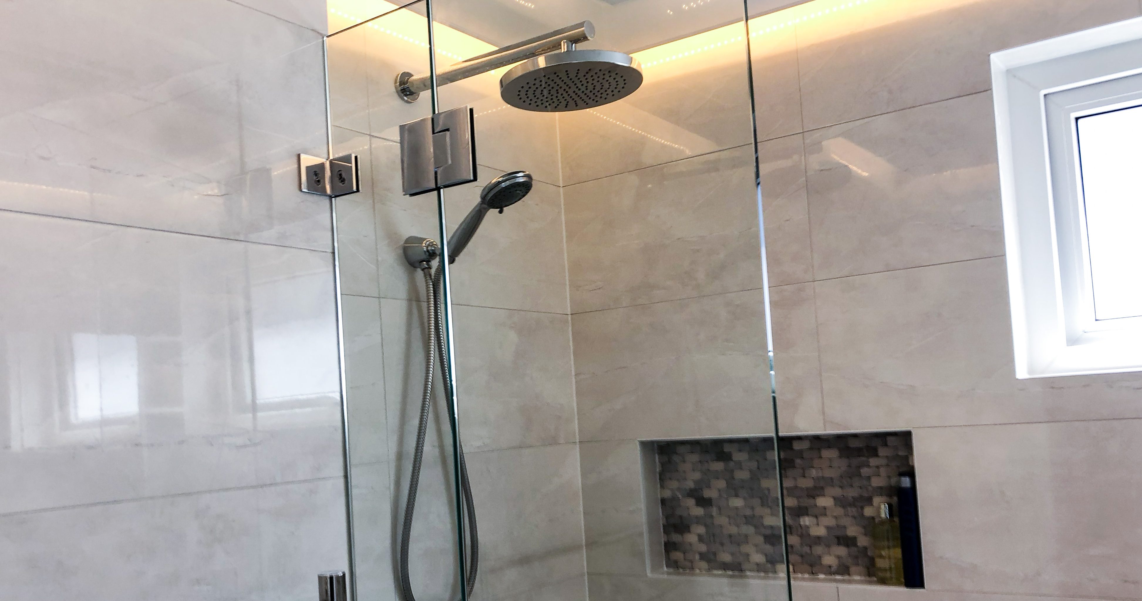 Beautiful chrome rainfall shower with hand held shower rose, shower niche and feature lighting in drop down ceiling - bathroom renovation by Master Bathrooms & Kitchens.