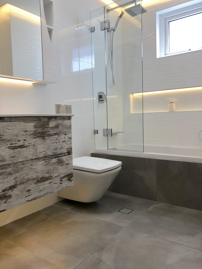 Stunning shower bath combination with rainfall shower rail, hand held shower rose, LED lit shower niche and pivot frameless shower screen.