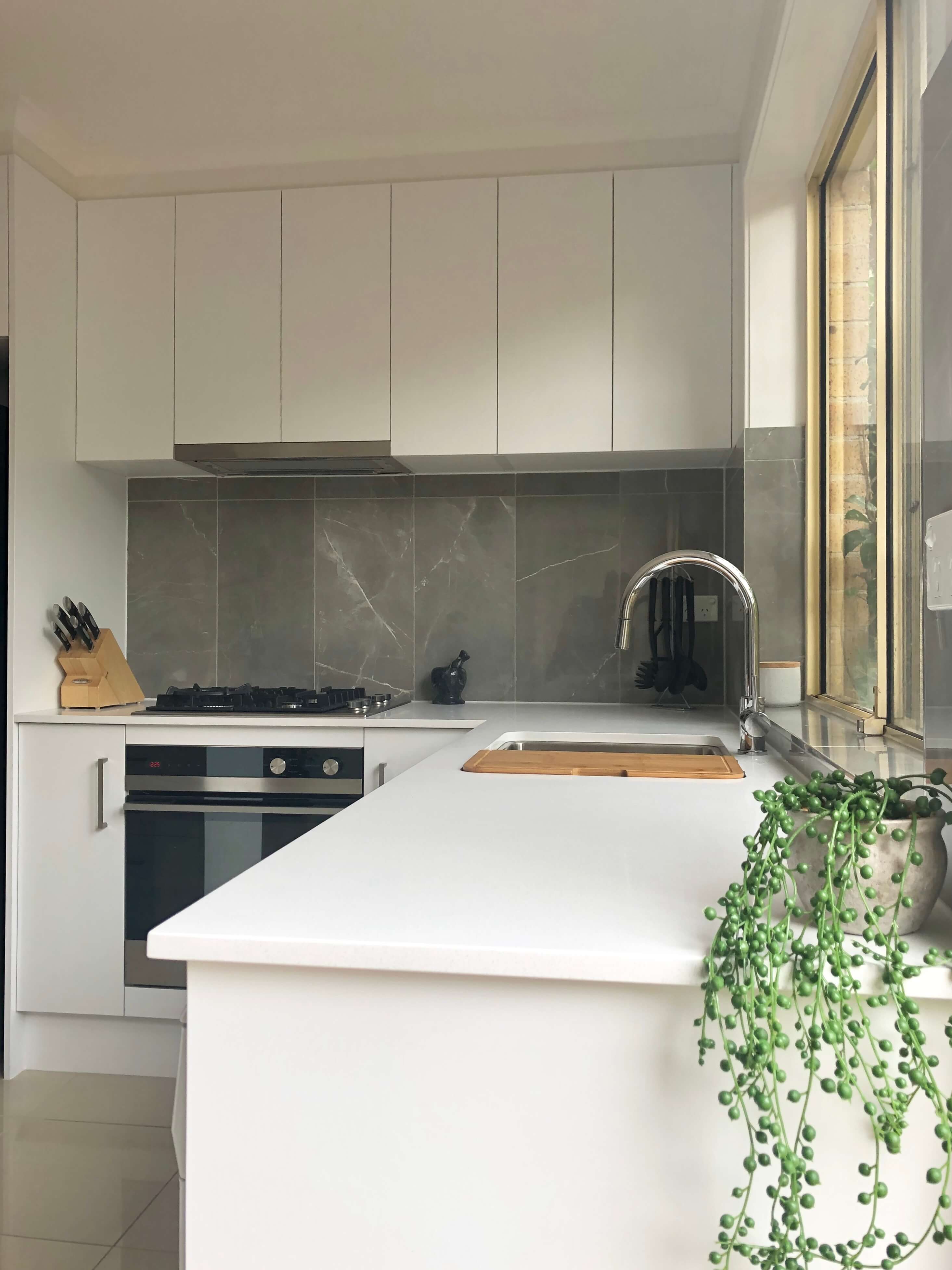 Stunning tiled splashback using faux marble 300 x 600mm porcelain rectified tile and beautiful undermount sink with arc mixer tap - kitchen renovation by Master Bathrooms & Kitchens.
